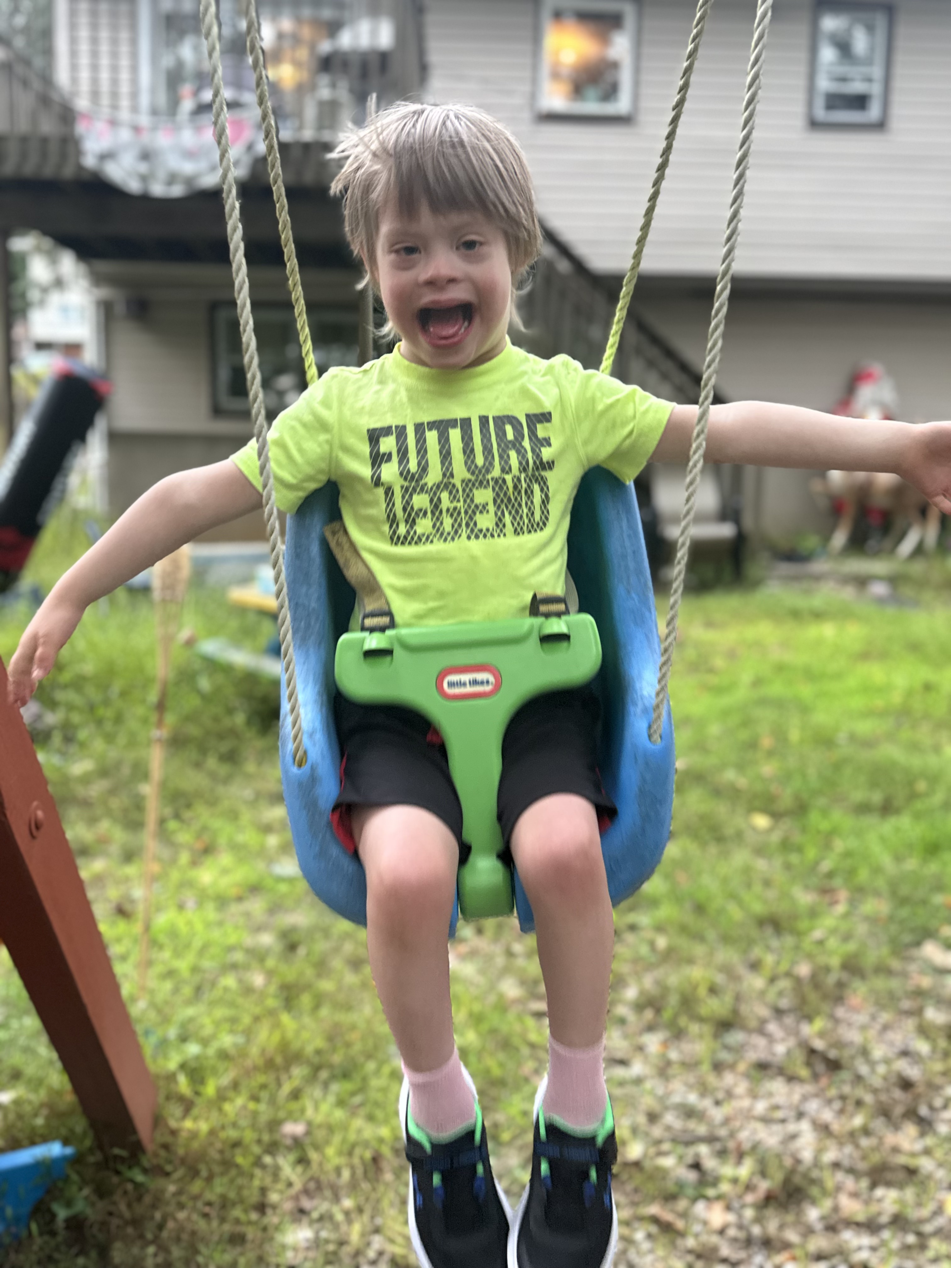 A joyful child on a backyard swing — one of the individuals Klean IQ supports.